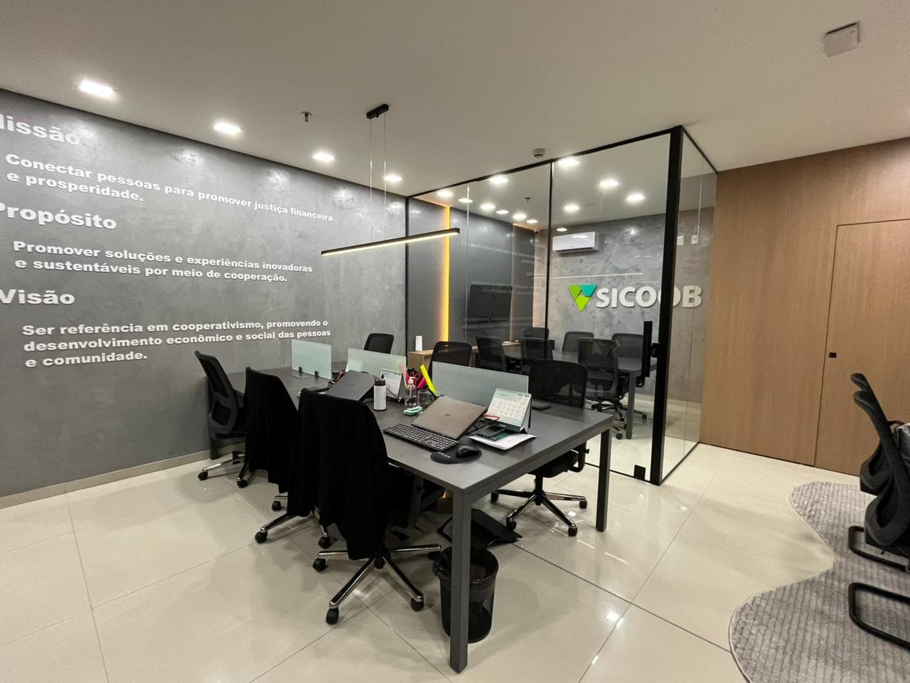 Escritório corporativo com sala de reunião em vidro e estações de trabalho